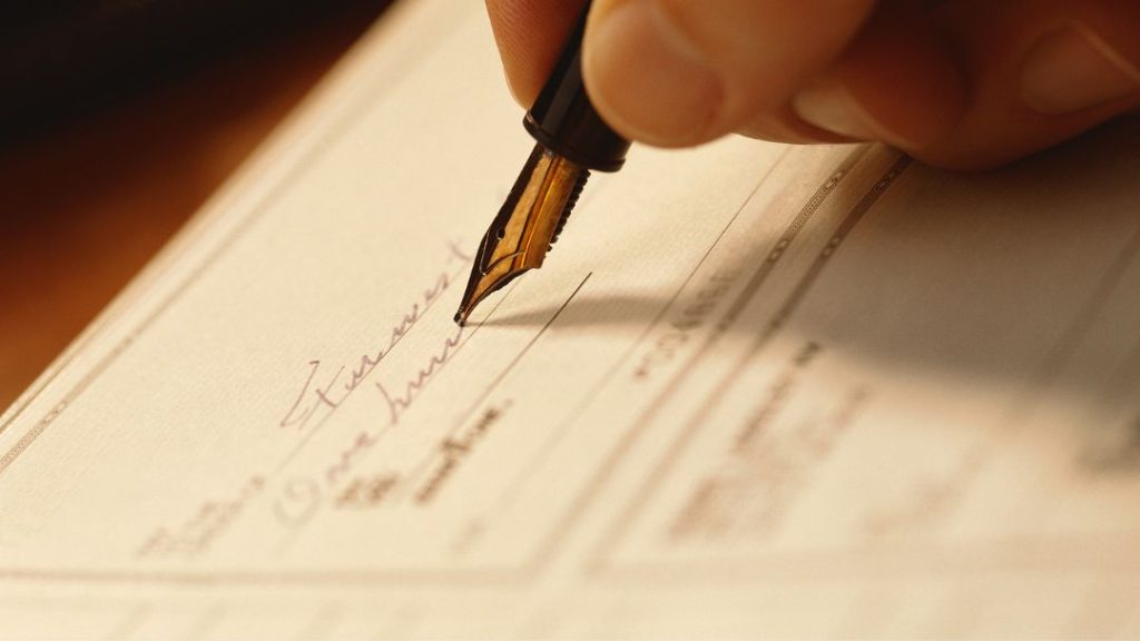 person's hand writing a check