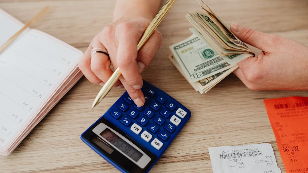 person using calculator with cash in hand